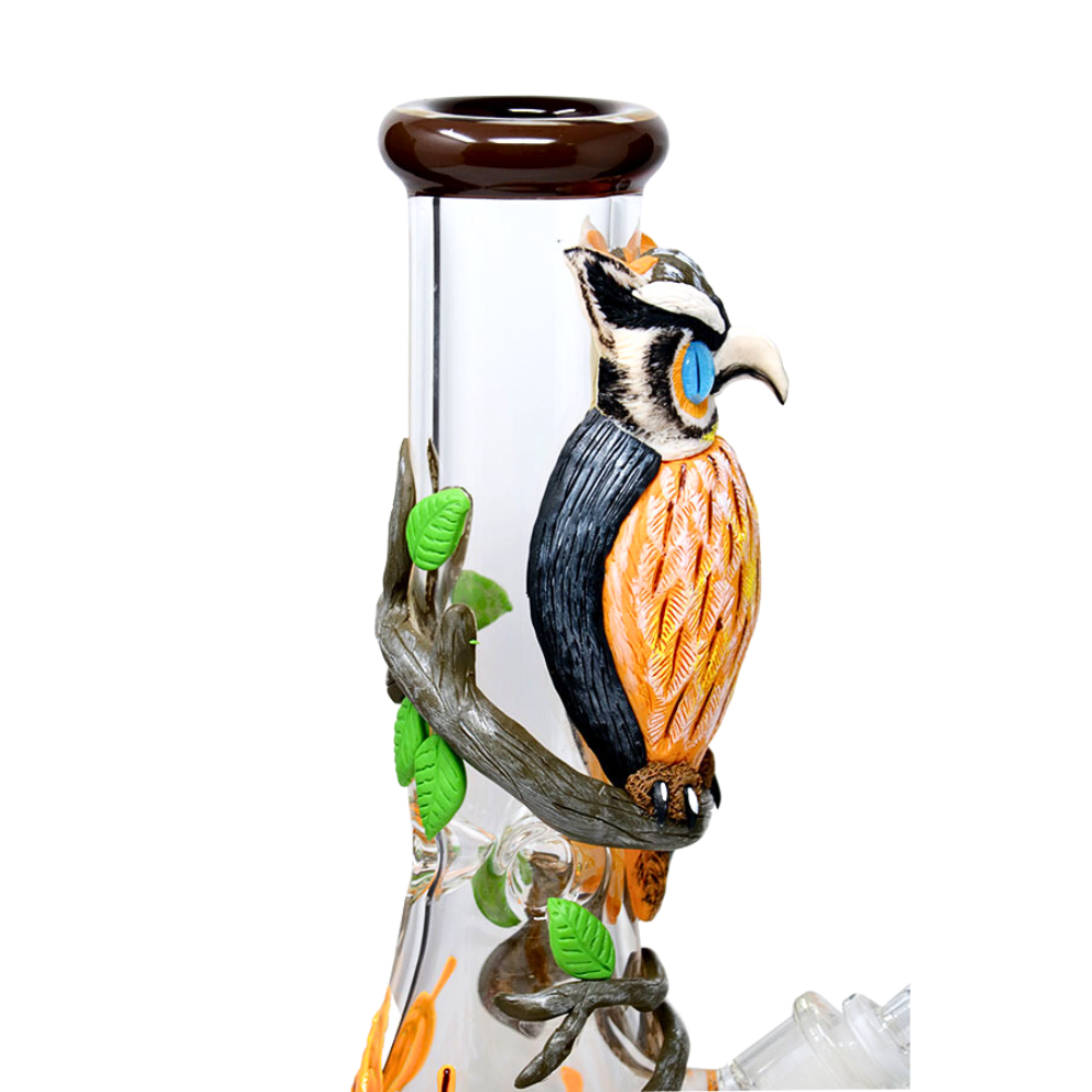 A high-quality borosilicate glass beaker with a unique 3D wrap design featuring an owl motif. The beaker is equipped with a herb bowl, down stem, and ice notches, and has a glow-in-the-dark feature.