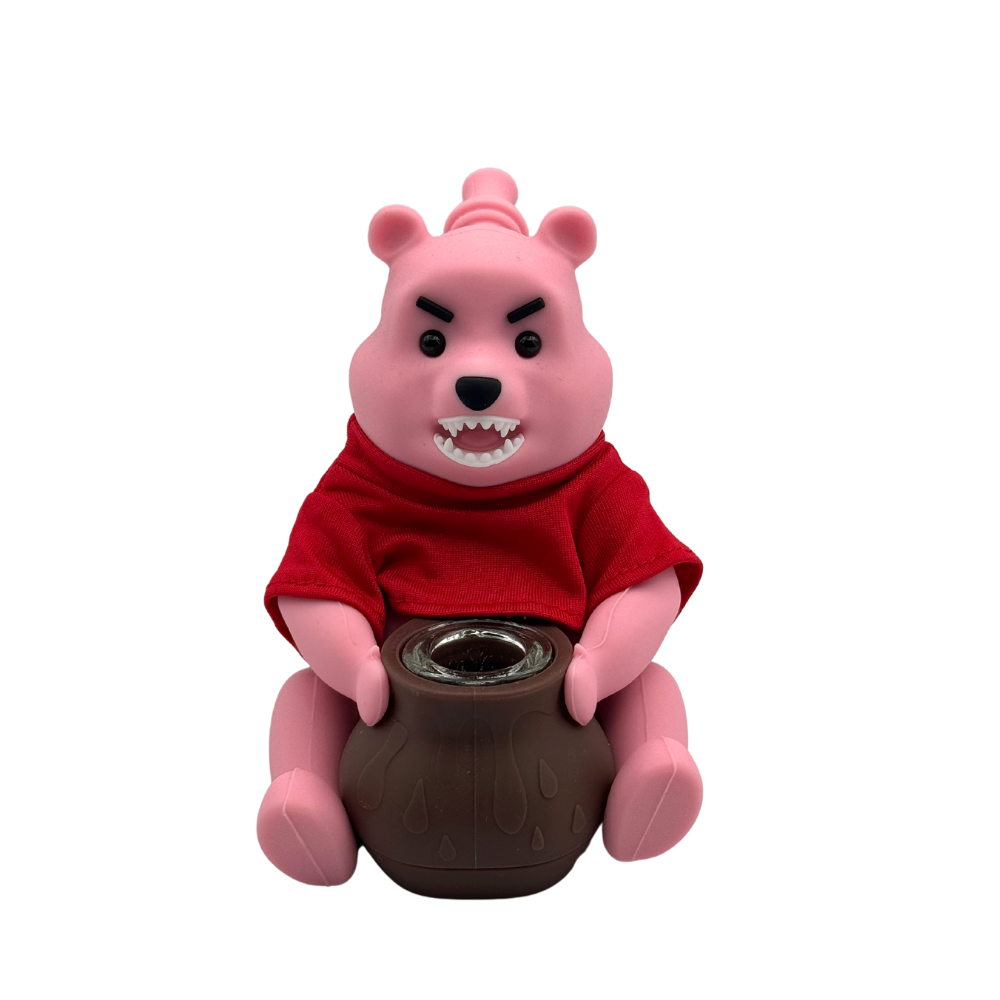 Pink bear figurine with a red shirt and a brown base on a white background